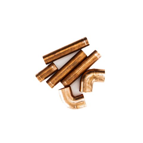 Six short lengths of copper pipe and two elbow fittings heaped together, their surfaces warm orange-gold and polished to a soft shine.