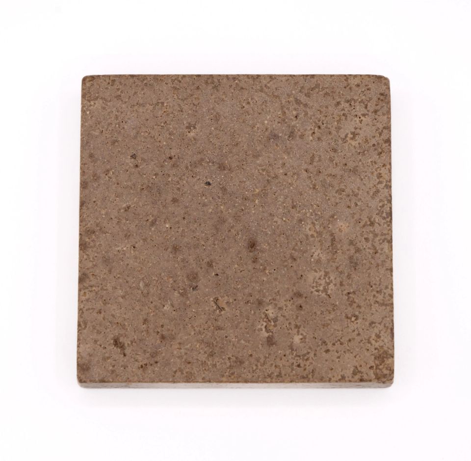 A square tile in muted grey-brown, its surface finely speckled with darker particles.