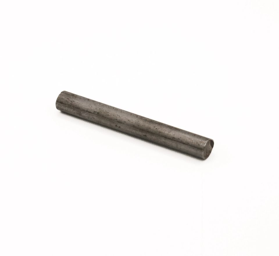 A short steel rod lying at an angle, its surface dull grey with faint darker mottling and a brighter cut end.
