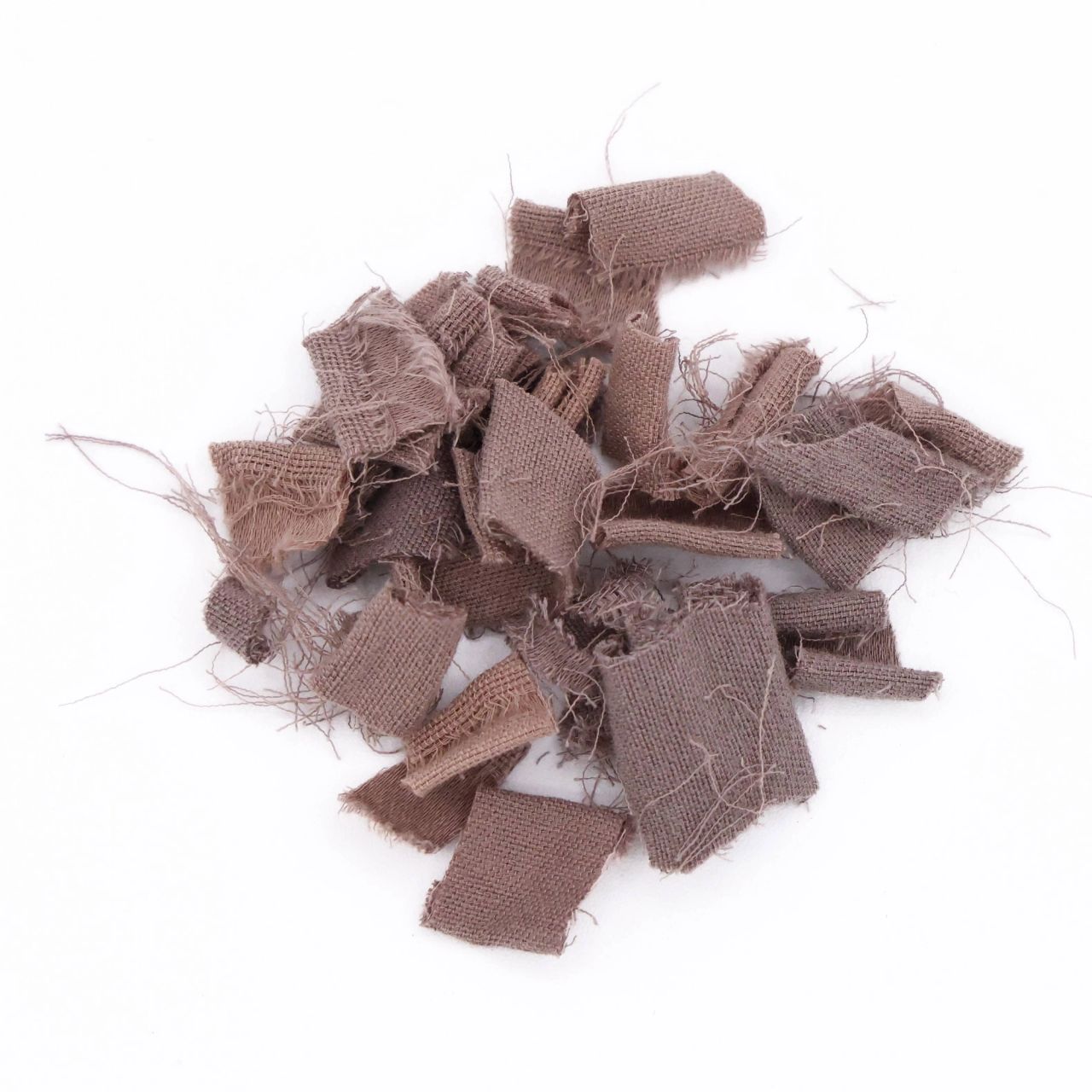 A heap of frayed fabric scraps in dusty mauve, cut into small rectangles with loose threads bristling from every edge.