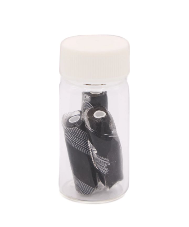 The black rods packed upright in a small clear vial with a white screw cap, their white cores and spiral markings visible through the glass.