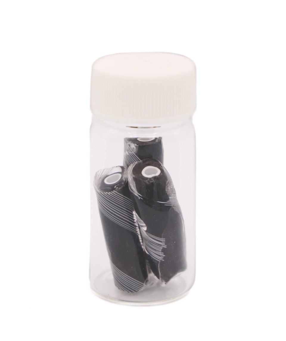 The black rods packed upright in a small clear vial with a white screw cap, their white cores and spiral markings visible through the glass.