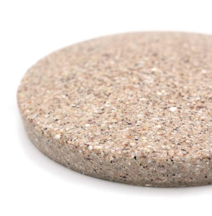 The tile cropped close at an angle, its sandy speckled face and thick rounded edge filling the frame.
