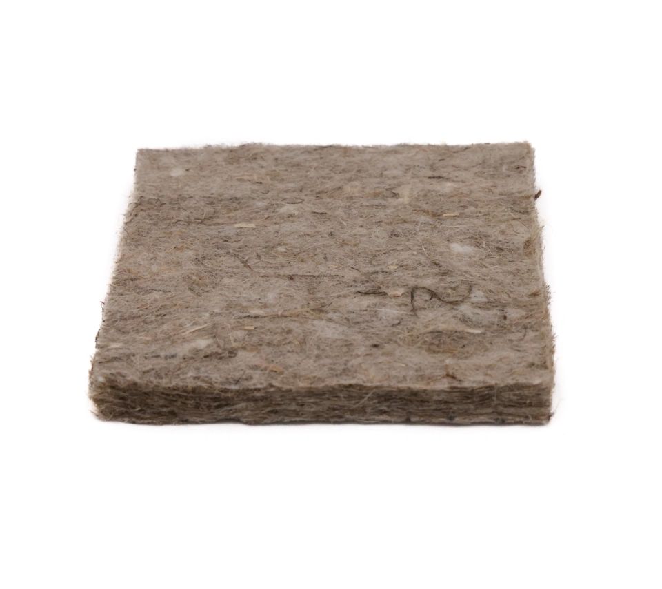 The pad at an angle from above, its greyish felted surface flecked with paler fibres and its edge softly compressed.