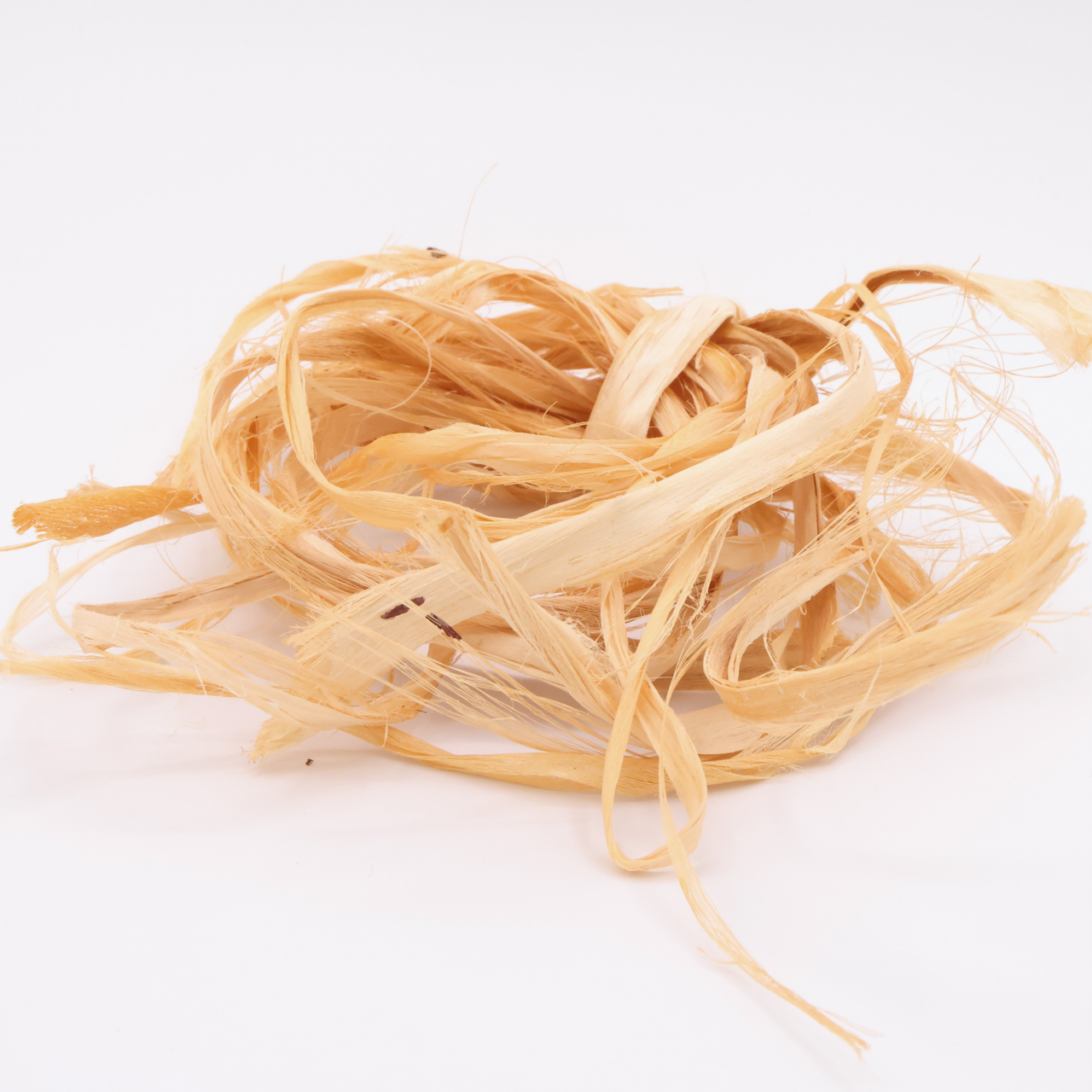 A loose tangle of tulip poplar inner bark in pale apricot, flat ribbons looping over one another with fine threads splitting from their edges.
