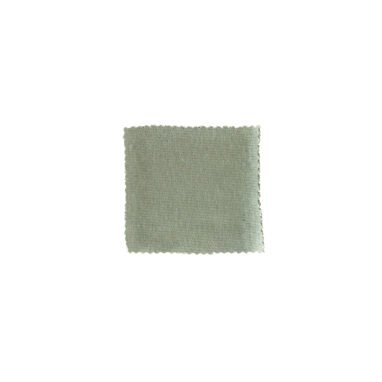 A small square swatch of sage-green knit with a smooth, close, faintly diagonal surface and lightly scalloped edges.