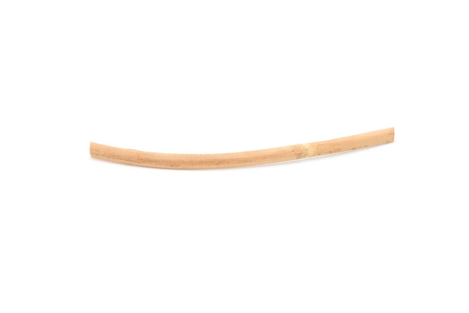 A single slender rattan reed curving gently, pale honey-coloured and split at one end.