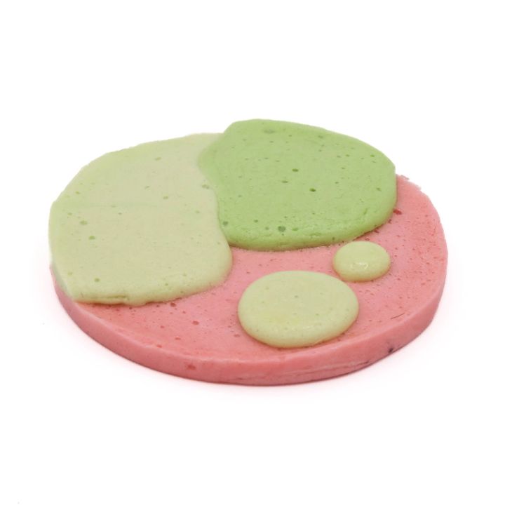 A round disc of moulded foam, a pink base with pale green and olive patches spreading across it and three smaller green dots.
