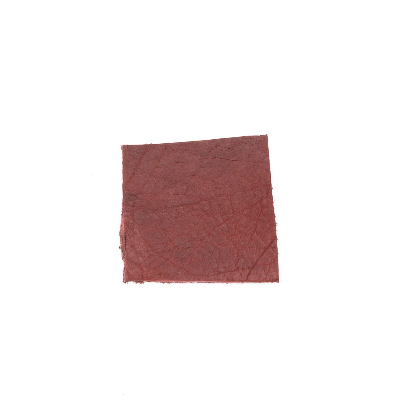 A square of vegetable-tanned cowhide in deep oxblood red, its surface faintly veined with a natural grain.