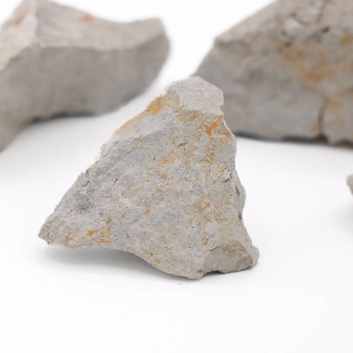 A close view of one chunk, its broken face pale grey and chalky with rust-orange staining in the crevices.