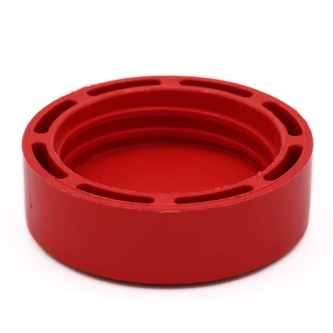 A wide red screw cap seen from above at an angle, its outer rim deeply ribbed and its interior a smooth glossy disc.