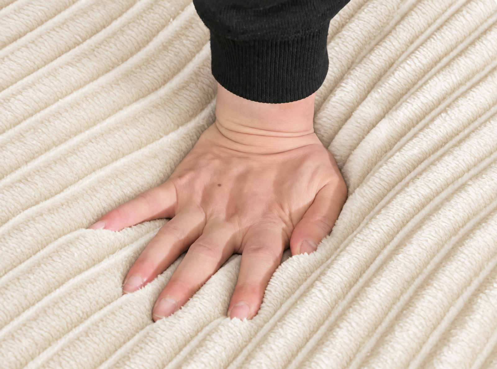 A close-up of cream-white wide-wale corduroy showing its raised ribs and channels.