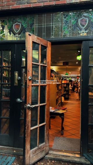 A doorway under stained-glass grape vines opens into a bookshop with green pendant lamps.