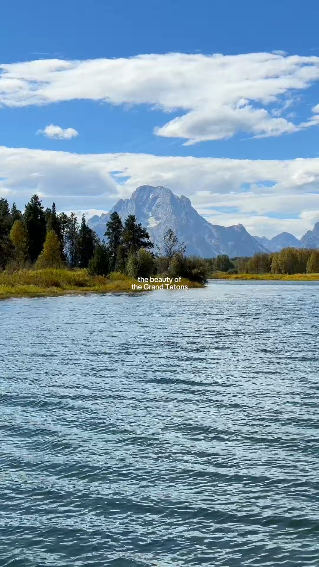 Blue water and trees beneath the Grand Teton mountains.