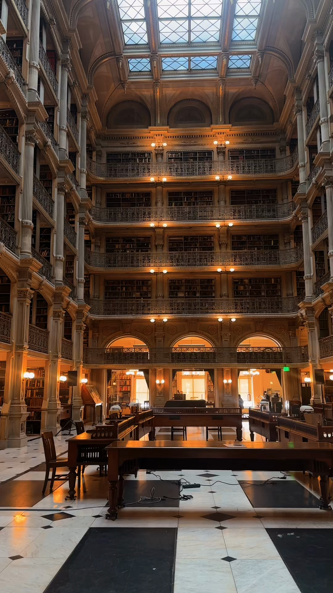 A multi-story library reading room with ornate balconies and a glass roof.