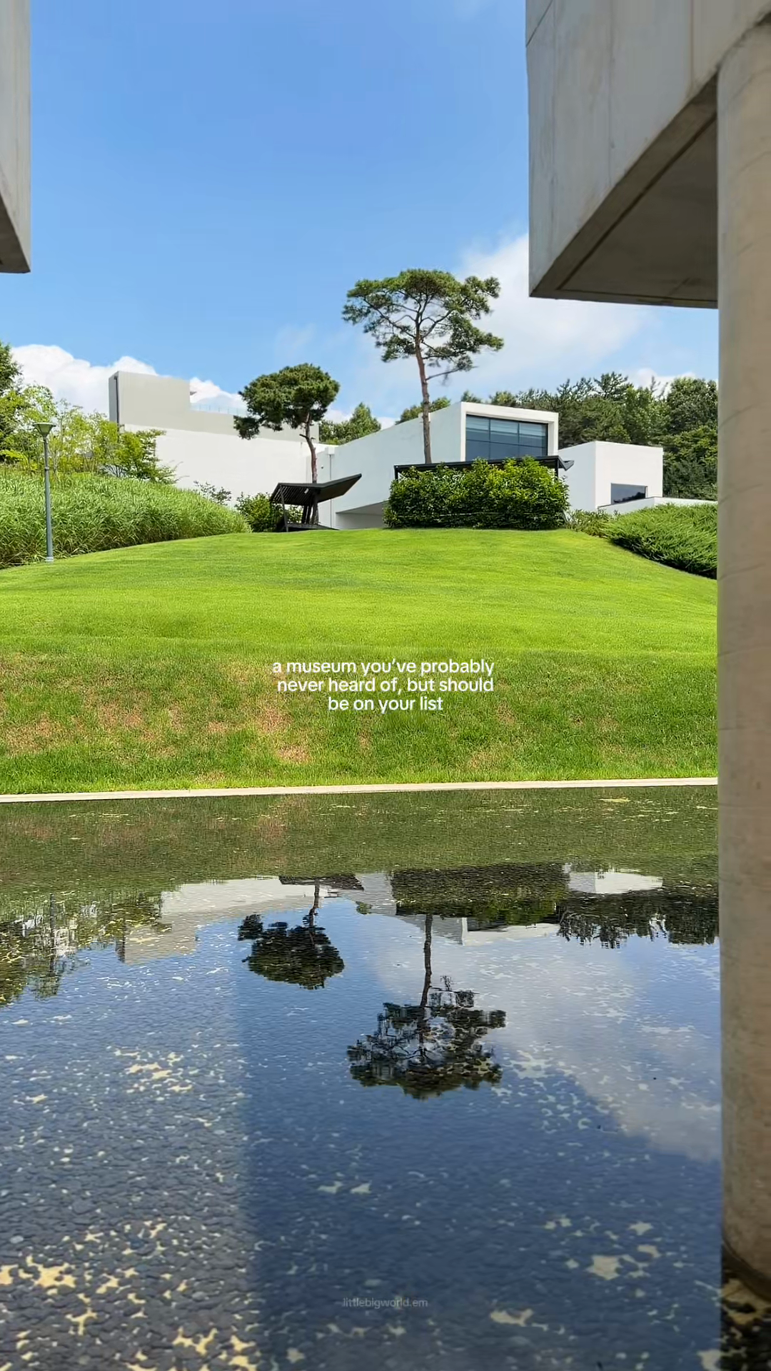 White museum walls, trees, and green lawn reflected in water at Namwon.