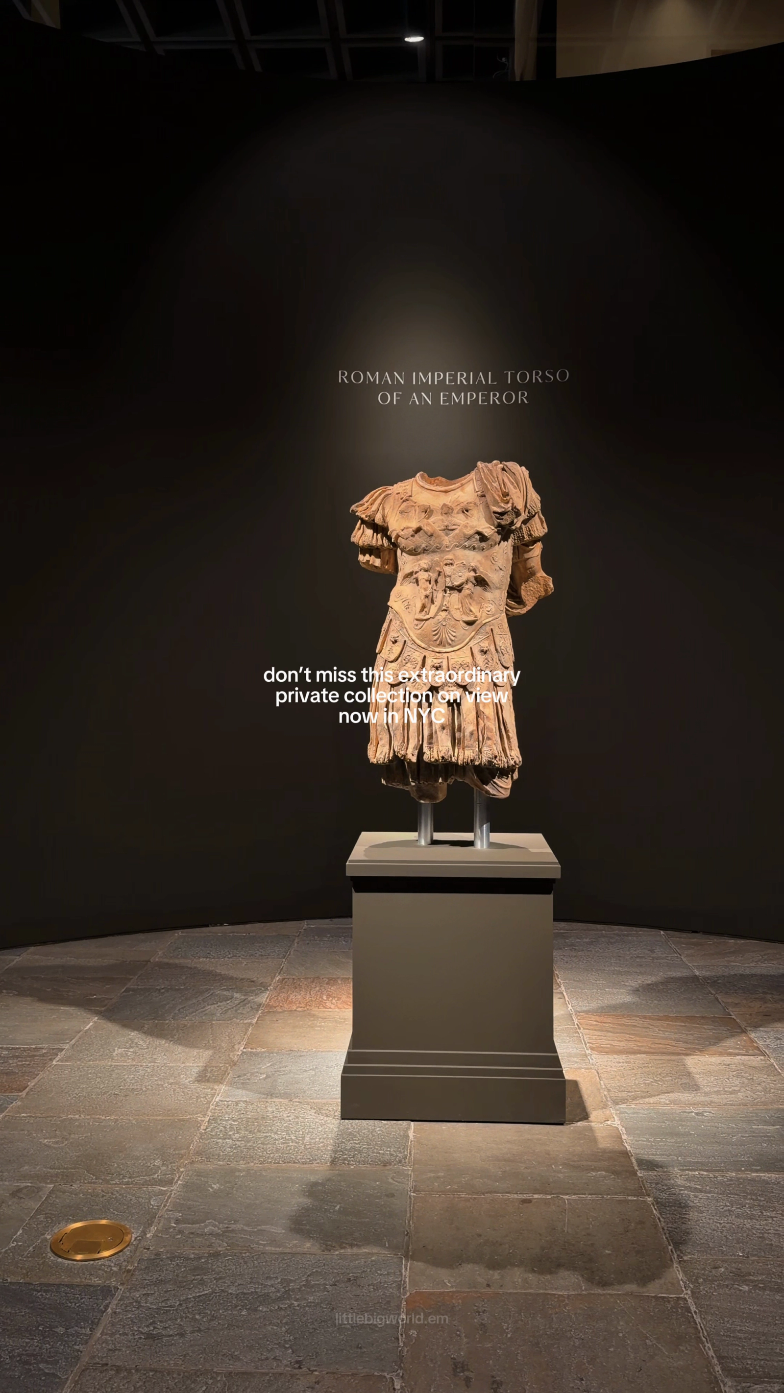 An ancient sculpted torso displayed in a dark gallery.