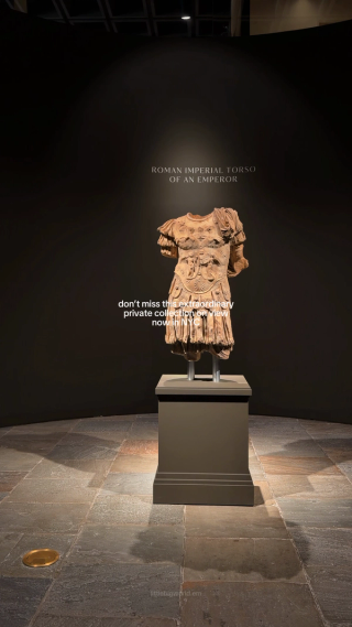 An ancient sculpted torso displayed in a dark gallery.