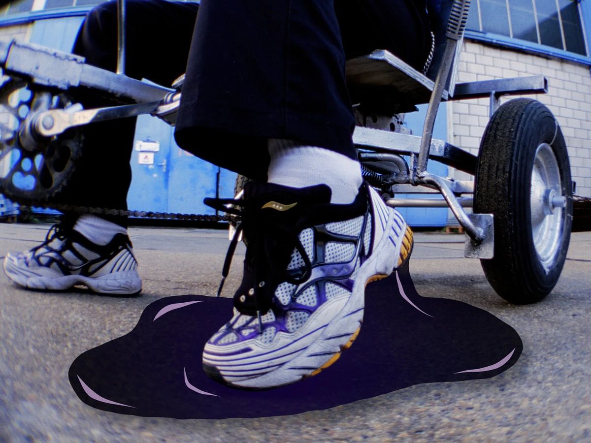 A white sneaker steps into a black puddle next to the wheel of a wheelchair.