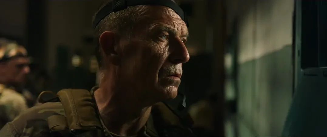 Close-up of an older soldier in a beret, in a dark room.