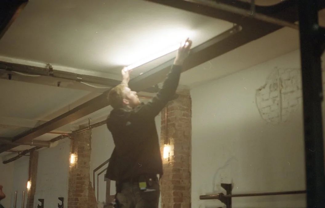 Analogue photo: a crew member reaches up to a lamp on a ceiling.