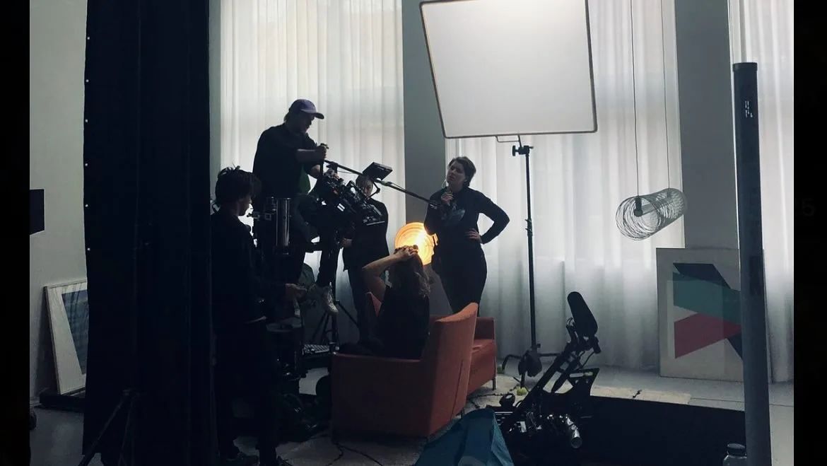 Behind the scenes of Als de beat dropt: crew around the camera in a room with white curtains and a softbox.