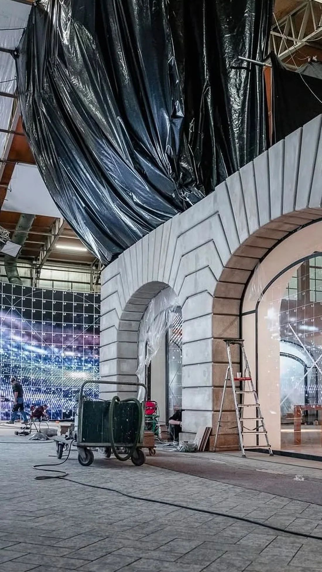 Behind the scenes: a set with curved white facades and black plastic in a large hall.