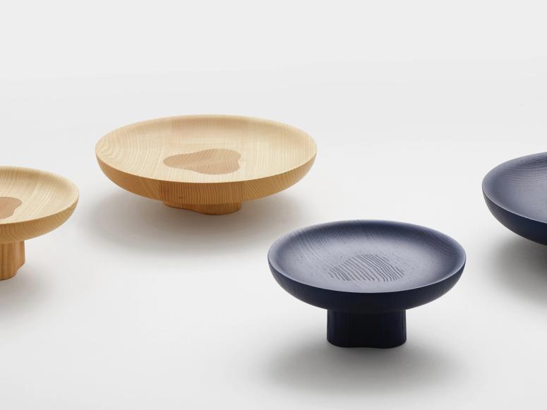 Black and natural wooden bowls on small, built-in platforms that raise them off the table.