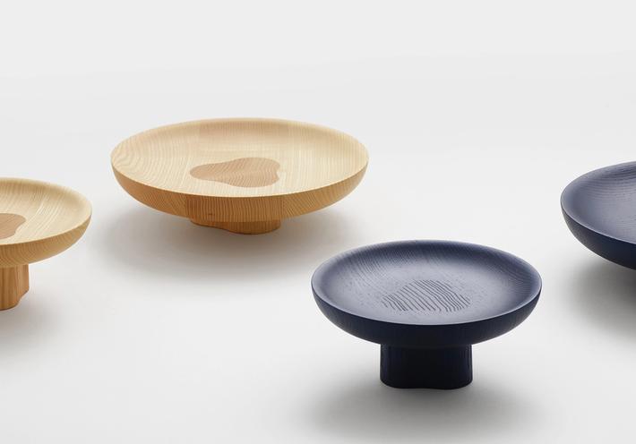 Black and natural wooden bowls on small, built-in platforms that raise them off the table.
