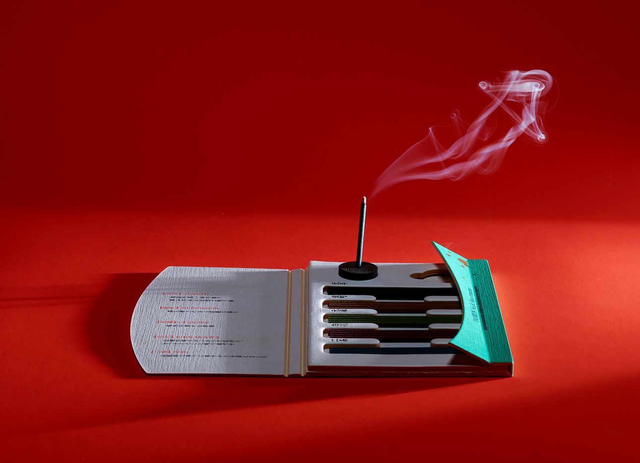 Incense burning on a pack of sticks on a red background.