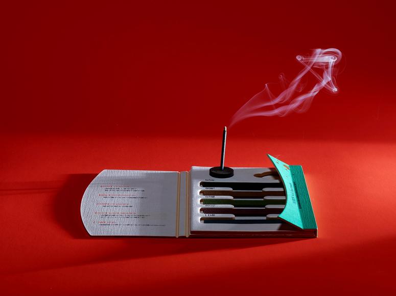 Incense burning on a pack of sticks on a red background.