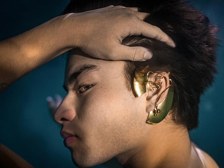A man wearing gold ear jewelry underwater.