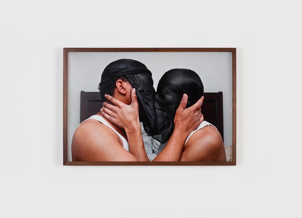 Two people kissing with black veils over their faces