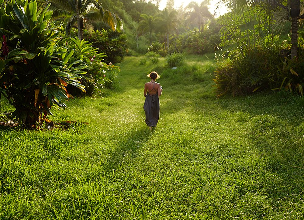 A woman walking in a field surrounded by palm trees.