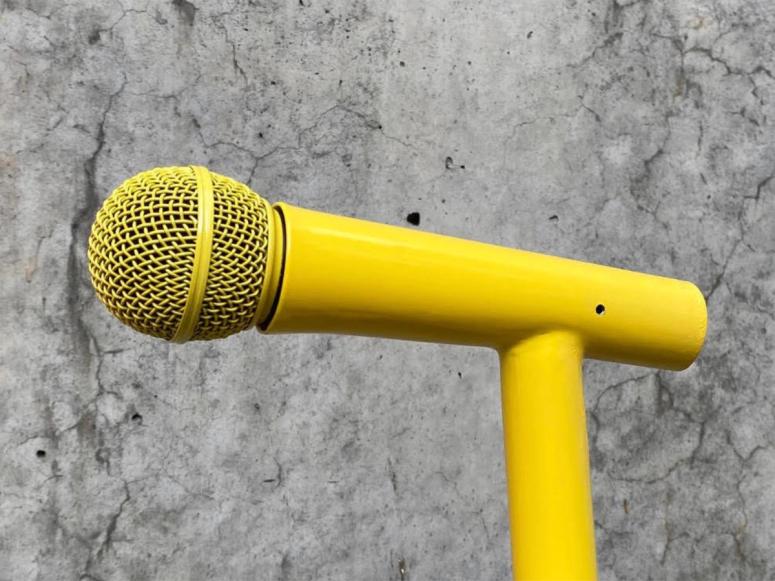 A yellow microphone on a concrete background.