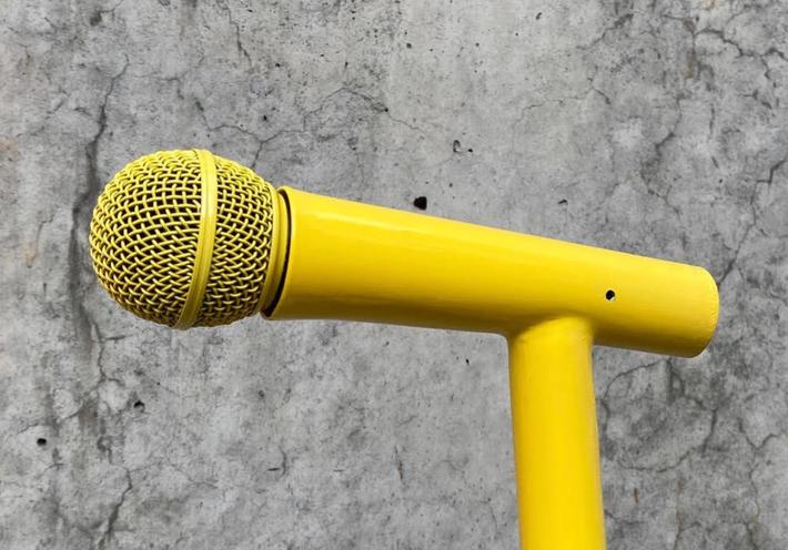 A yellow microphone on a concrete background.