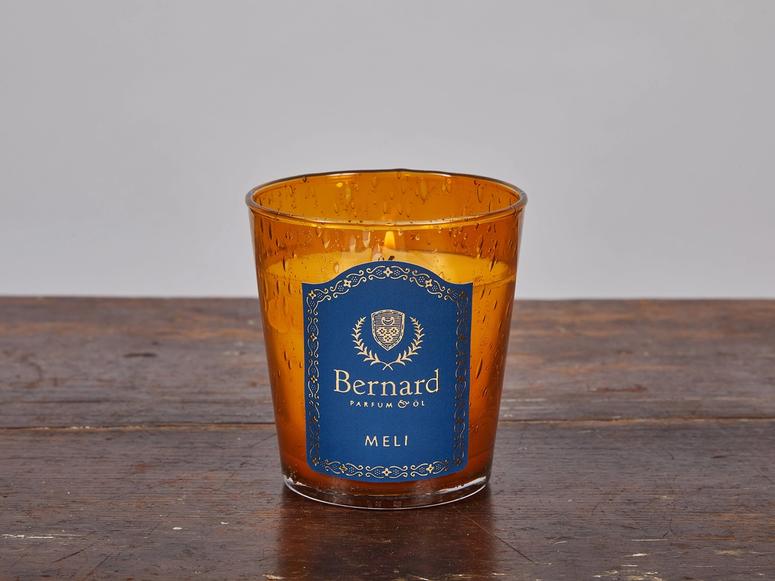 An orange and blue candle on a wood surface.