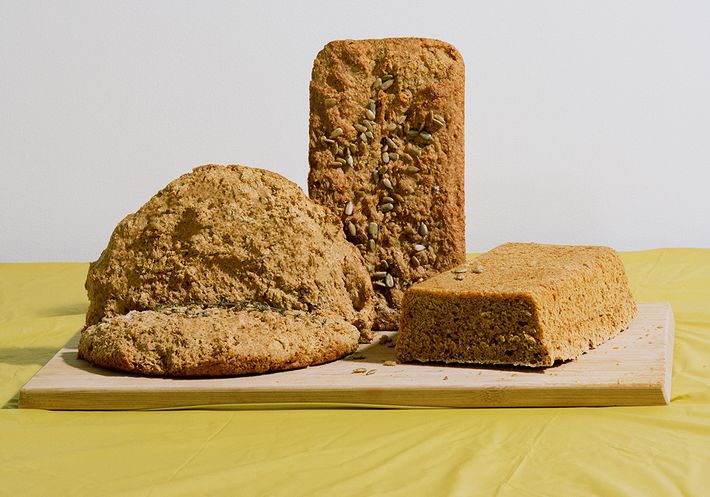 Three monolithic bread loaves on a yellow tablecloth.