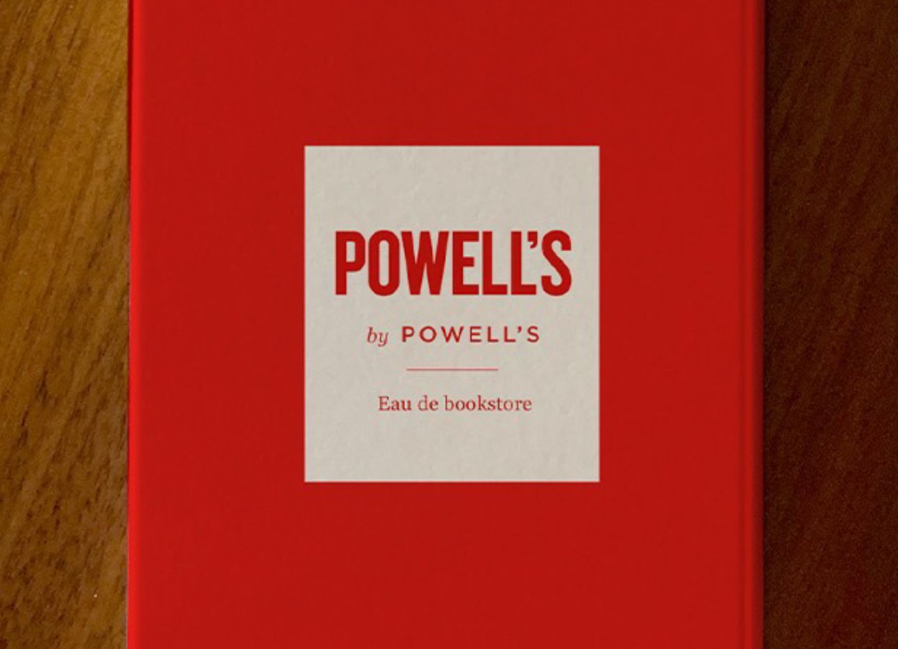 A red Powell's by Powell's book on a wooden table.