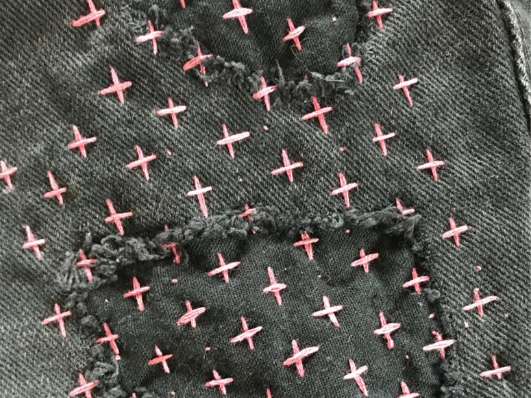 Black denim fabric with pink cross stitches