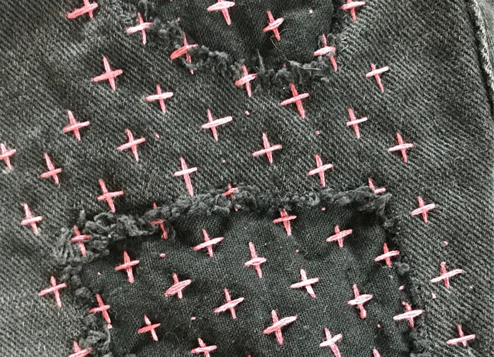 Black denim fabric with pink cross stitches