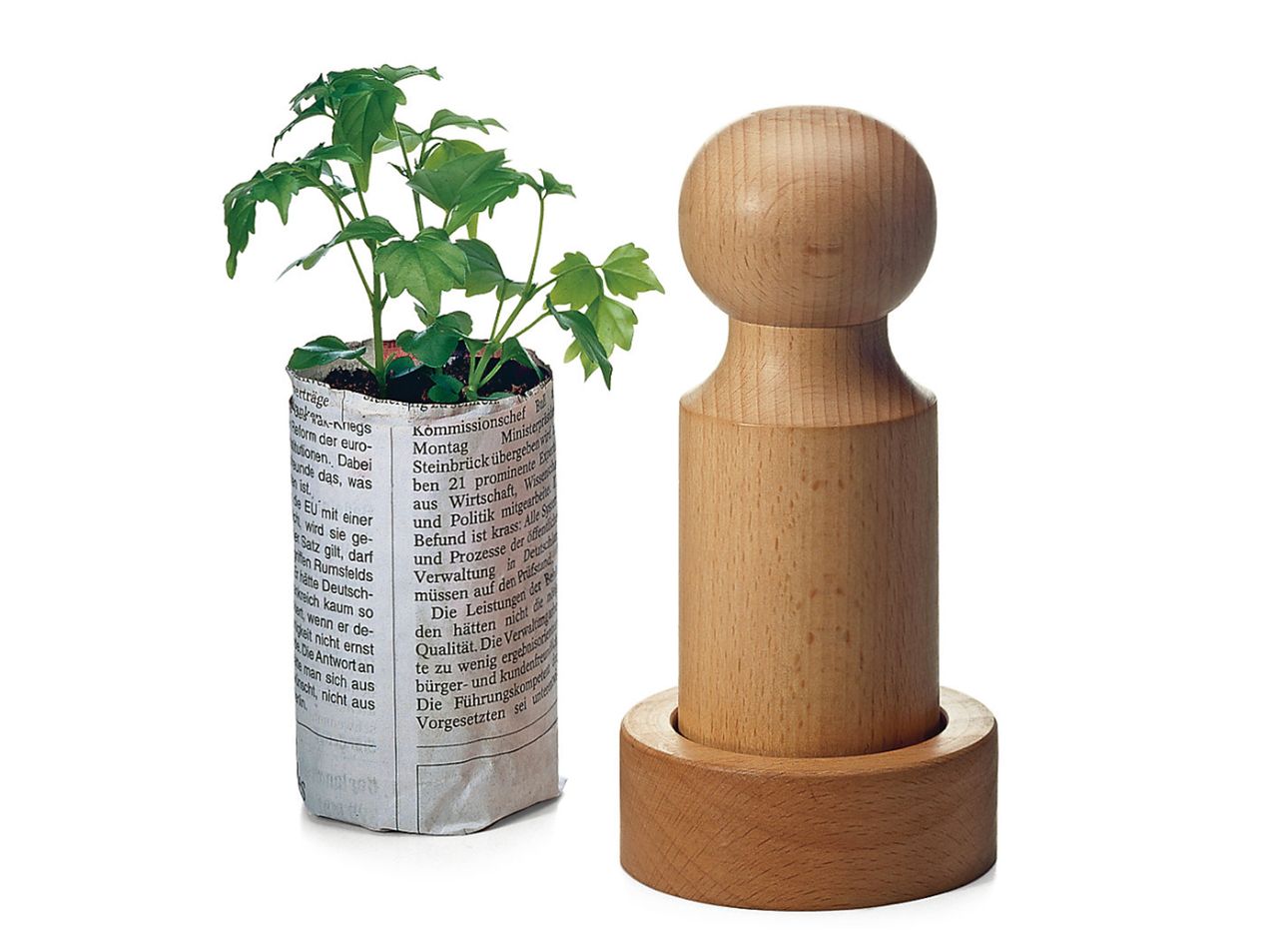 Manufactum's seed pot press next to a seedling.