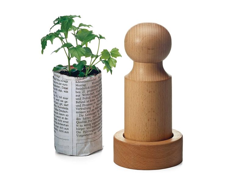 Manufactum's seed pot press next to a seedling.