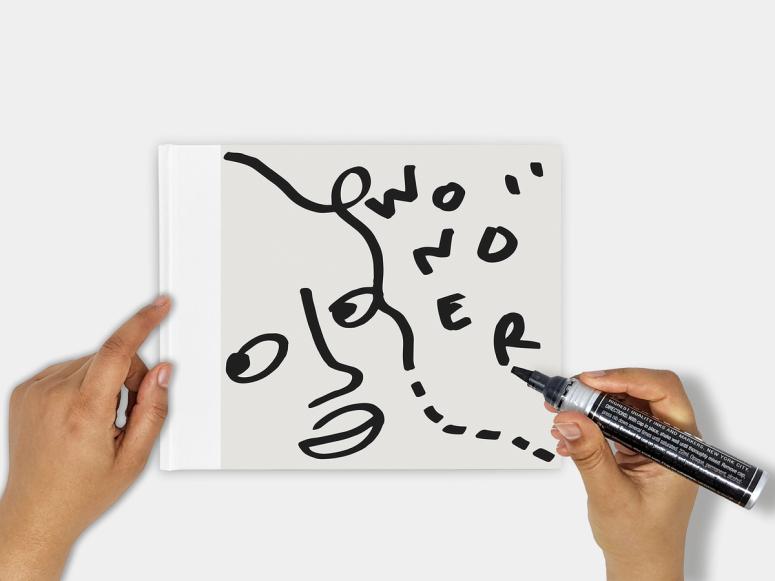 Shantell Martin's book, Wonder, with her hands holding a marker above it.