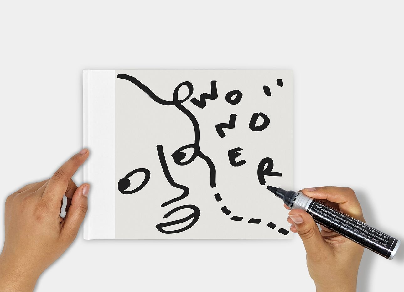 Shantell Martin's book, Wonder, with her hands holding a marker above it.