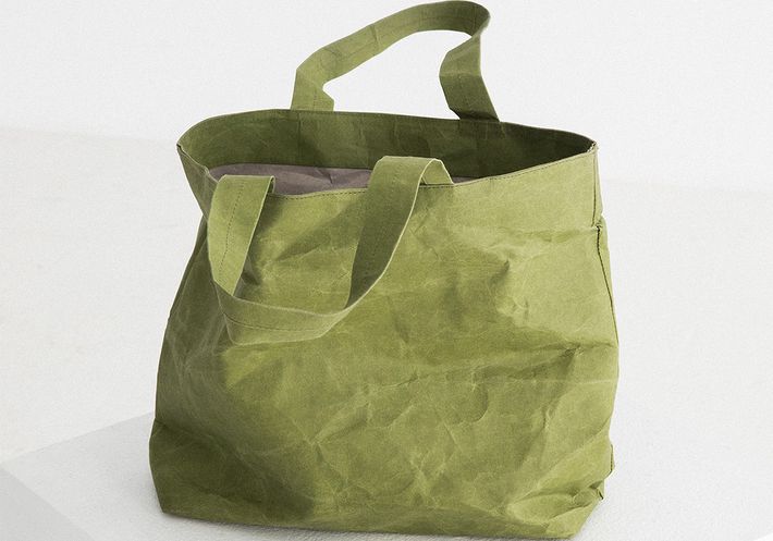 A crinkled green tote bag on a white plinth.