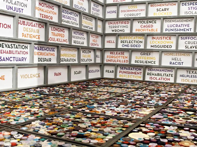 Interior of an art installation with walls covered in rainbow-colored words and phrases