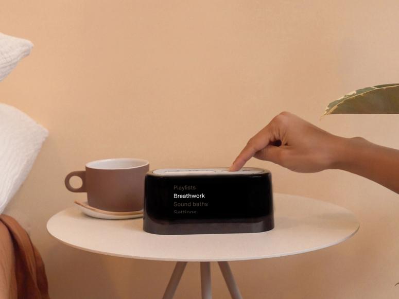 A black digital alarm clock on a pink bedside table