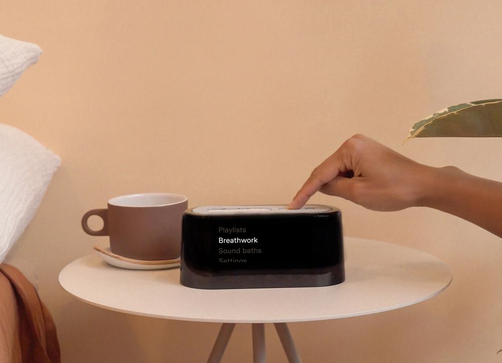 A black digital alarm clock on a pink bedside table