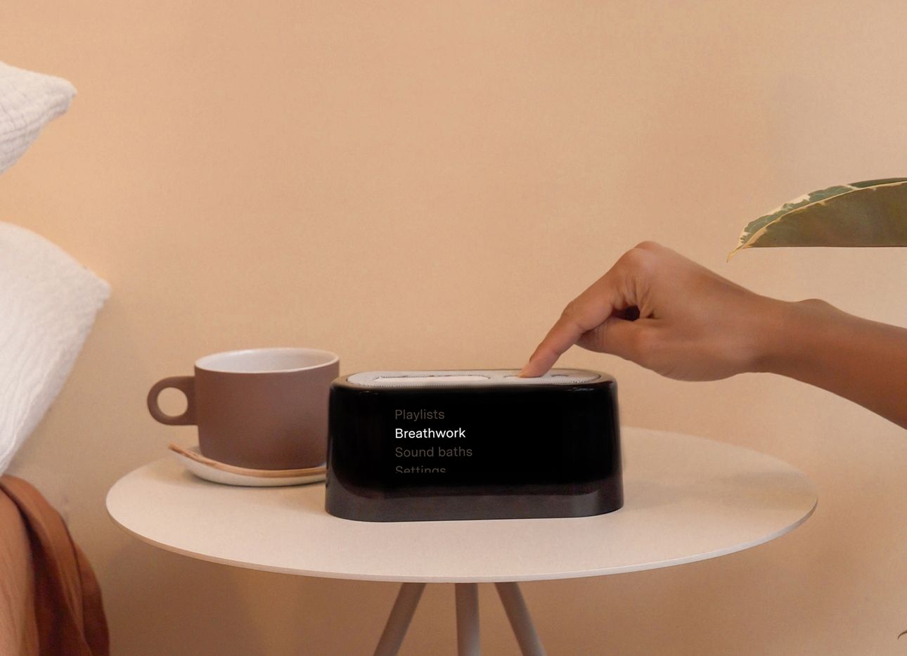 A black digital alarm clock on a pink bedside table